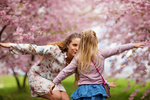 Beautiful blonde dutch mother and child daughter together in a Cherry Blossom Forest