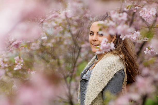 istock Beautiful Blonde Woman alone in Cherry Blossom Trees 1127073502