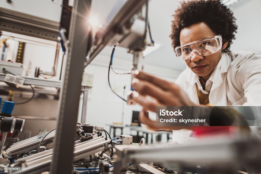 Negro mujer Ingeniero en industrial de la máquina en un laboratorio. - Foto de stock de Ingeniero libre de derechos