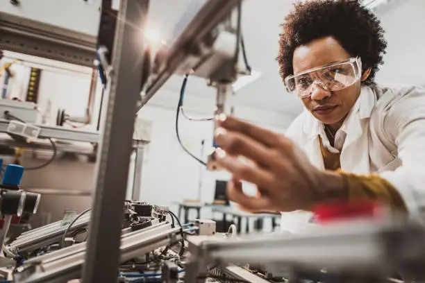 Photo of Black female engineer working on industrial machine in a laboratory.