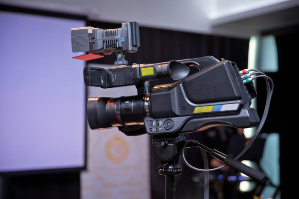 istock Professional digital camera with microphone on the tripod recording video .Camera recording publicity event . Press conference. Filming an event with a video camera. on the tripod in the room - Image 1127076115