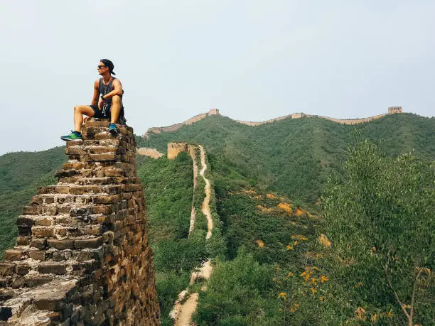 A man sitting on the Great Wall in China. There are still hidden gems at this so popular travel destination.