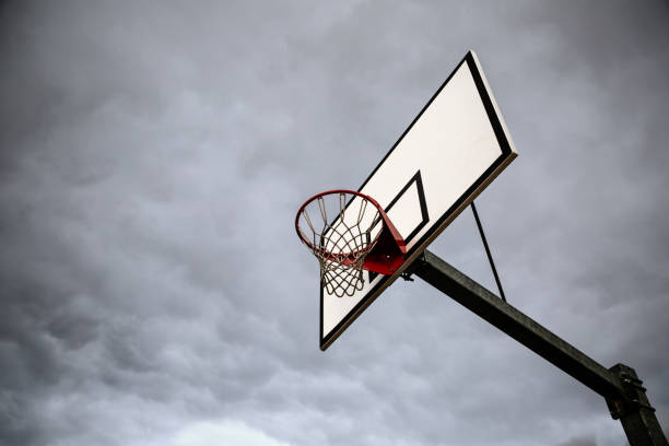 Basketball rim, board and net against cloudy grey sky