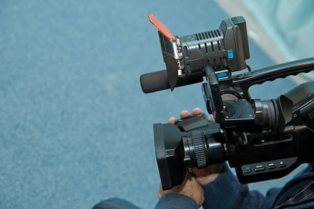 istock Covering an event with a video camera., Videographer takes video camera with free copy space for text., Video camera operator working with his equipment., close up of television operator with camera. 1127078228