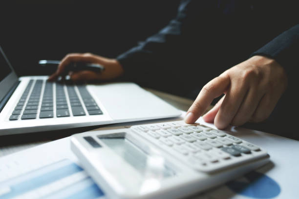 istock image of bookkeeper /  financial inspector calculating on investment data with documents and laptop in dark office room 1127079446