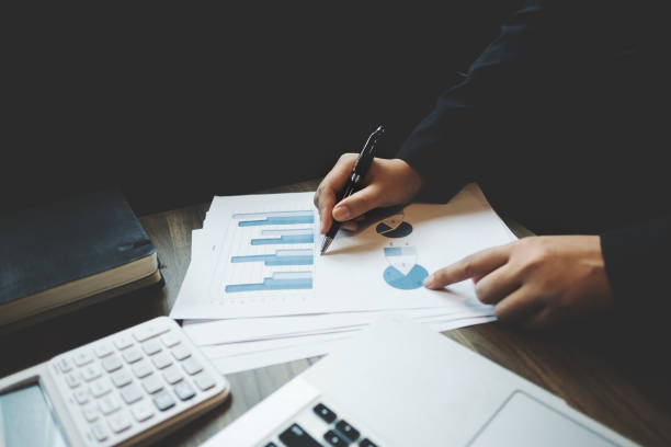 istock image of bookkeeper /  financial inspector calculating on investment data with documents and laptop in dark office room 1127079462