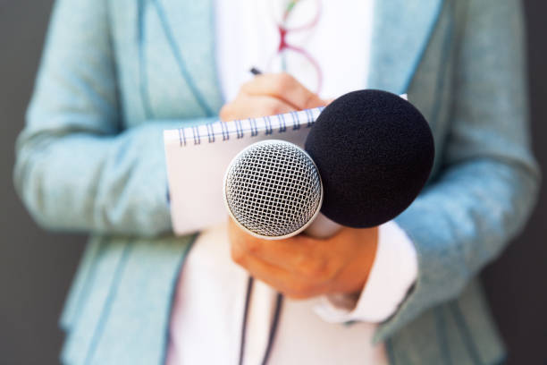 istock Female reporter at press conference, writing notes, holding microphone 1127079702