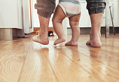 Father teaching baby to walk - rear view