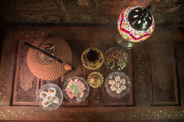 istock Arabian tea in glass with eastern snacks on vintage wooden surface. Eastern tea concept. Low light lounge interior with carpet. Empty space. 1127087212