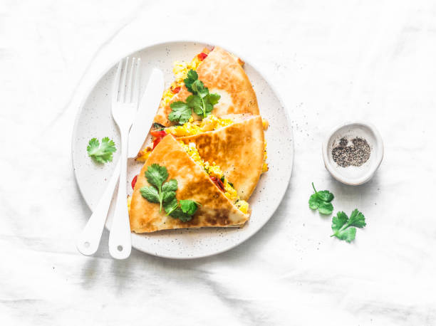 istock Scramble eggs vegetables ham quesadilla on a light background, top view. Tasty snack, tapas, breakfast 1127087905