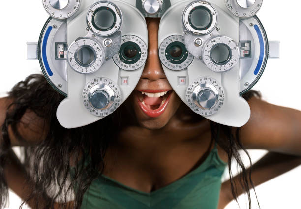 young and happy black afro american woman at hospital looking through optometric hospital device checking eyes having sight exam in ophthalmology health care isolated on white background - patient happiness cheerful optometrist imagens e fotografias de stock
