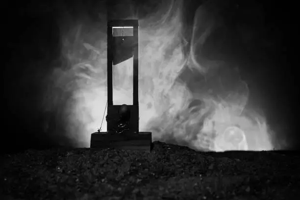 Horror view of Guillotine. Human at guillotine on a dark foggy background. Execution concept