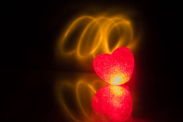 istock Blurred neon heart icon on a dark background. Copy space with red bright colorful heart on black background 1127089009
