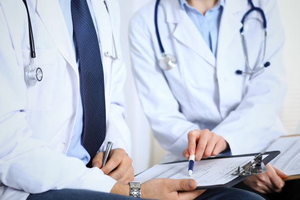 istock Two unknown doctors filling up medical form on clipboard, just hands closeup. Physicians asking question to patient or discussing medication program. Healthcare, insurance and medicine concept 1127093888