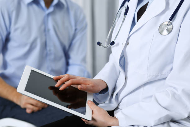 istock Female doctor using touchpad or tablet computer while consulting man patient in hospital. Medicine and healthcare concept 1127093900