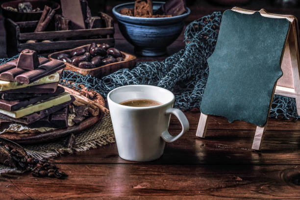 istock Assorted chocolate on a wooden table with copy space on a standing blackboard and a mug with hot chocolate 1127093948