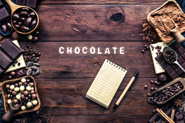 istock Assorted chocolate in old fashioned style with drawing board with a note pad and copy space frame sign 1127094086