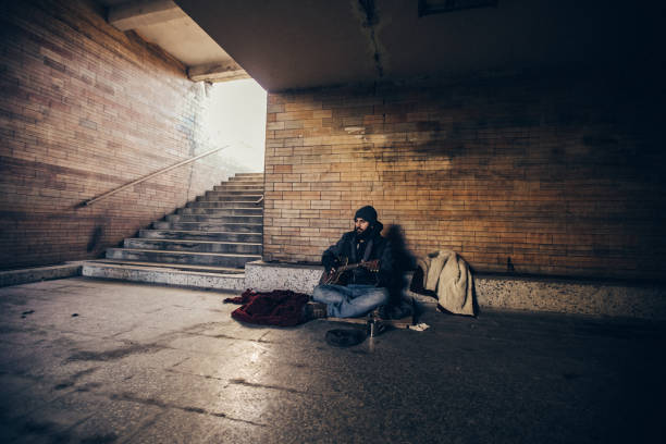 istock Homeless man playing guitar in underpass tunnel 1127095427