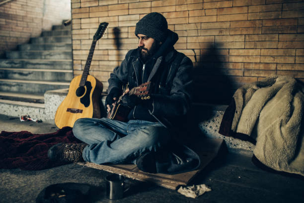 istock Homeless man playing guitar in underpass tunnel 1127095469