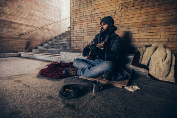 istock Homeless man playing guitar in underpass tunnel 1127096996