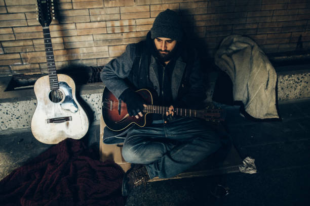 istock Homeless man playing guitar in underpass tunnel 1127097033