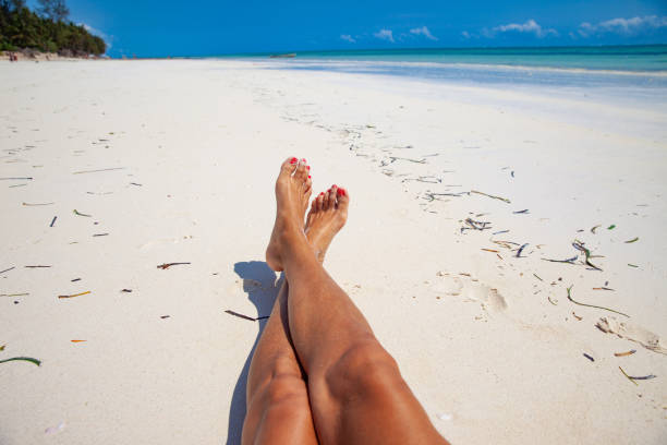 istock Female legs on sandy beach - personal perspective 1127097107