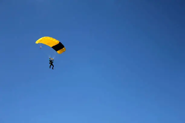 Photo of Unrecognizable skydiver on clear blue sky,