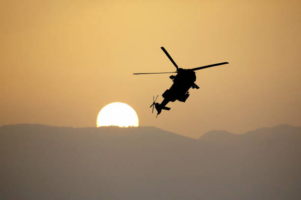 istock Silhouette of a flying helicopter against the setting sun 1127102489