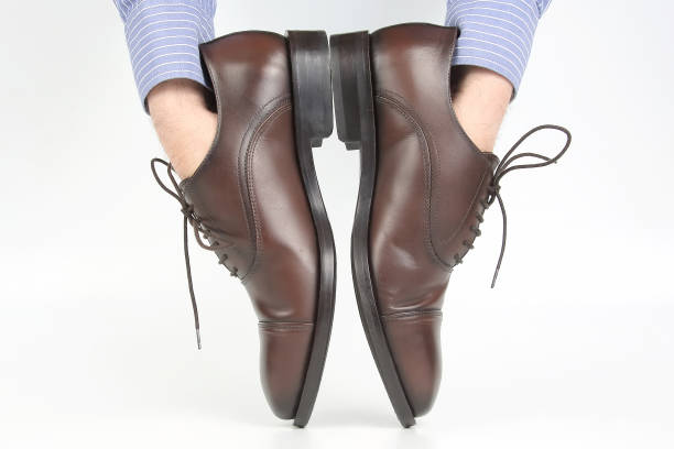 istock Classic brown shoes worn on the hands on a white background 1127102604