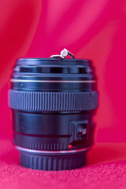Engagement ring for the photographer A gold ring on the lens of the camera. Elegant, red background. złoto stock pictures, royalty-free photos & images