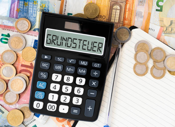 German word Grundsteuer (property tax or land tax) on display of pocket calculator with euro bills and coins in background close-up of German word Grundsteuer (property tax or land tax) on display of pocket calculator with euro bills and coins in background german language photos stock pictures, royalty-free photos & images