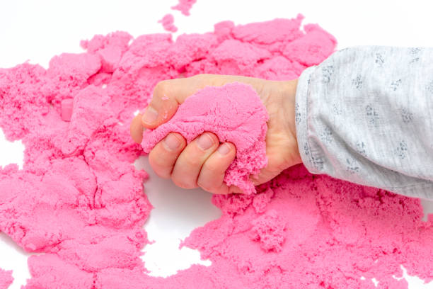 istock Hands of a kid playing with pink magic sand. 1127105084