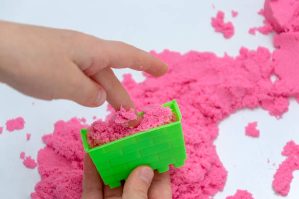 istock Hands of a kid playing with pink magic sand. 1127105085