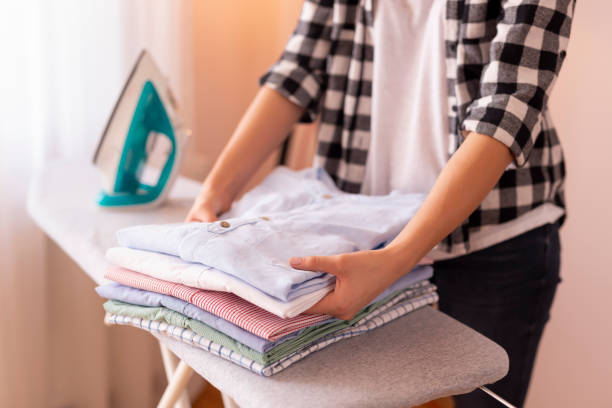 donna pieghevole vestiti puliti - iron laundry cleaning ironing board foto e immagini stock