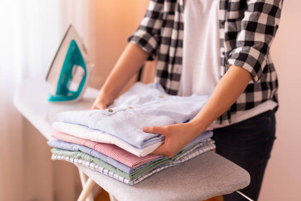 Woman folding clean clothes Detail of female hands folding clean clothes on the ironing board after doing the ironing iron laundry cleaning ironing board stock pictures, royalty-free photos & images