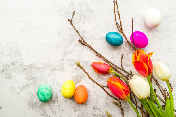 istock pussy willow branches and tulips with colored eggs on white marble background background, copy space, top view 1127107932