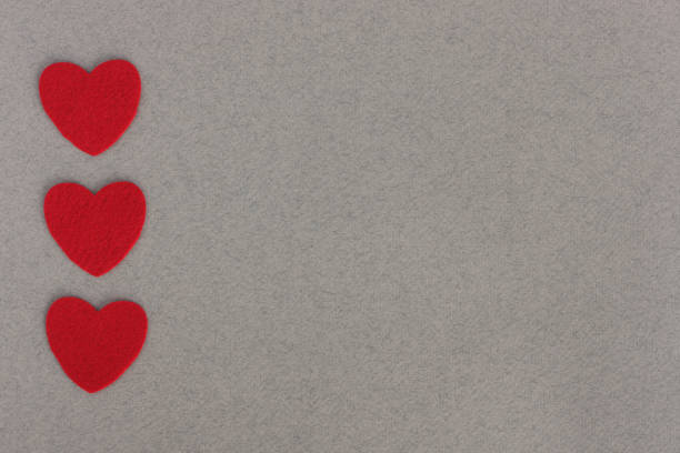 red felt hearts on grey background with place for inscription red felt hearts on grey paper background with space for inscription интерьер помещен�ий stock pictures, royalty-free photos & images