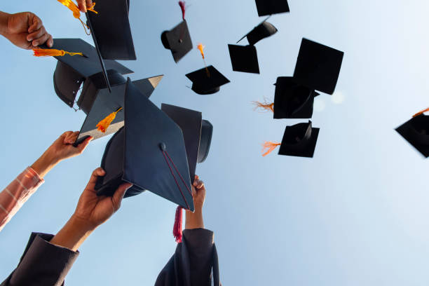 istock Black hat of the graduates floating in the sky. 1127115457