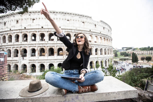 istock Young girl pointing ahead sitting in front of Coliseum 1127115986