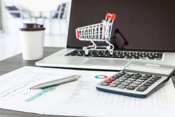 istock Business e-commerce online and financial accounting concept., Calculator and a pen on data fact sheet in front of personal computer laptop background., Customer shopping e-payment of web development. 1127116307