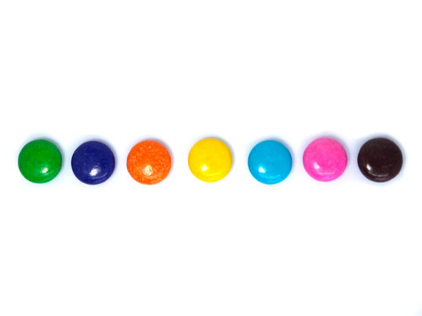 top view of colorful button-shaped chocolates or candy-coated chocolate arrange into horizontal rows on white background with space for text. clipping path - candy coated imagens e fotografias de stock