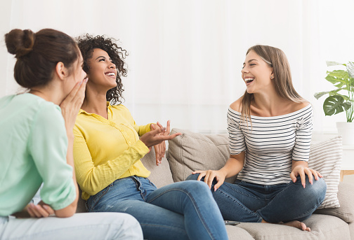 Diverse female friends talking, gossiping in the living room at home