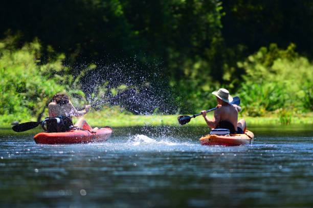istock Girl leaning away from cold water being splashed by boyfriend while kayaking on river 1127124253