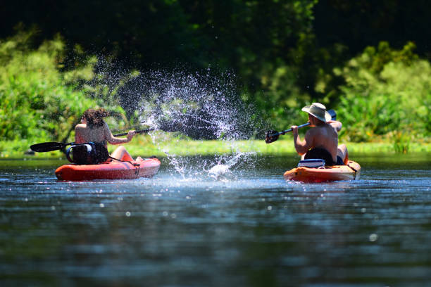 istock Girl recoiling away from cold water being splashed by boyfriend while kayaking on river 1127125038