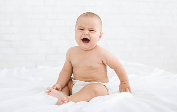 istock Cute crying baby boy on bed in morning 1127126679
