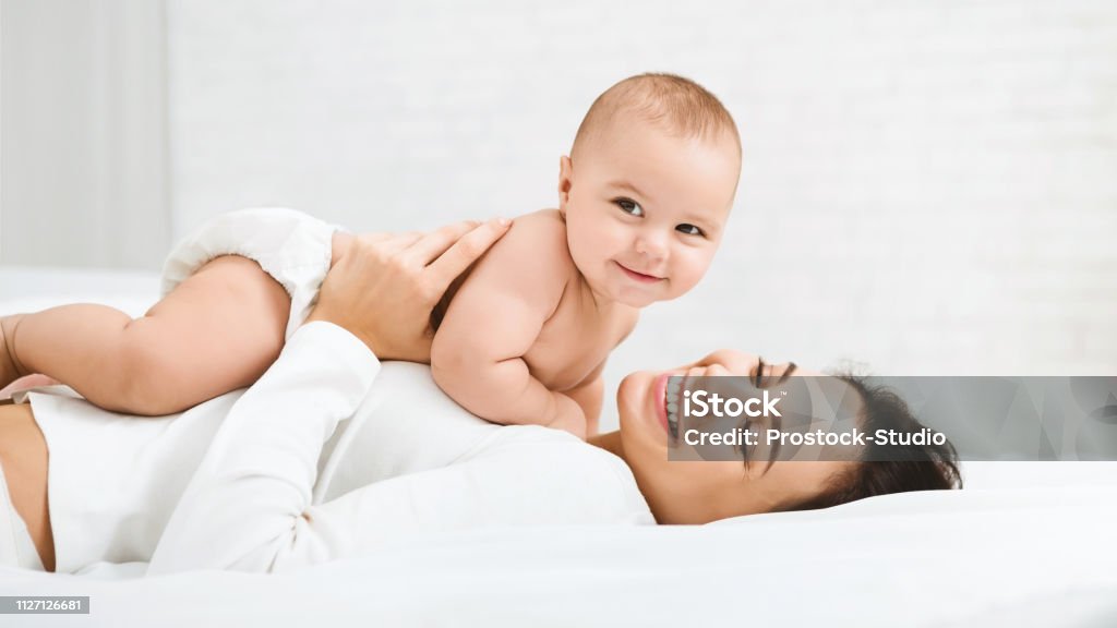 Mamma e bambino in pannolino che giocano in camera da letto - Foto stock royalty-free di Bebé