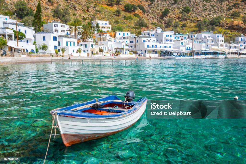 Fishing boat and the scenic village of Loutro in Crete, Greece Crete Stock Photo