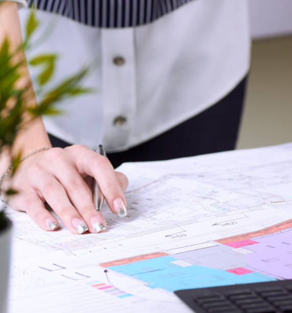 istock Real estate creative studio office. Architect woman working on architectural project for interior design. Woman's hands over the table with the drawing. 1127132138