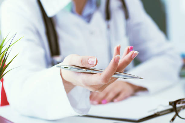 istock Female doctor explaining patient symptoms or asking a question as they discuss together in a consultation. Just hands over the table. 1127132156