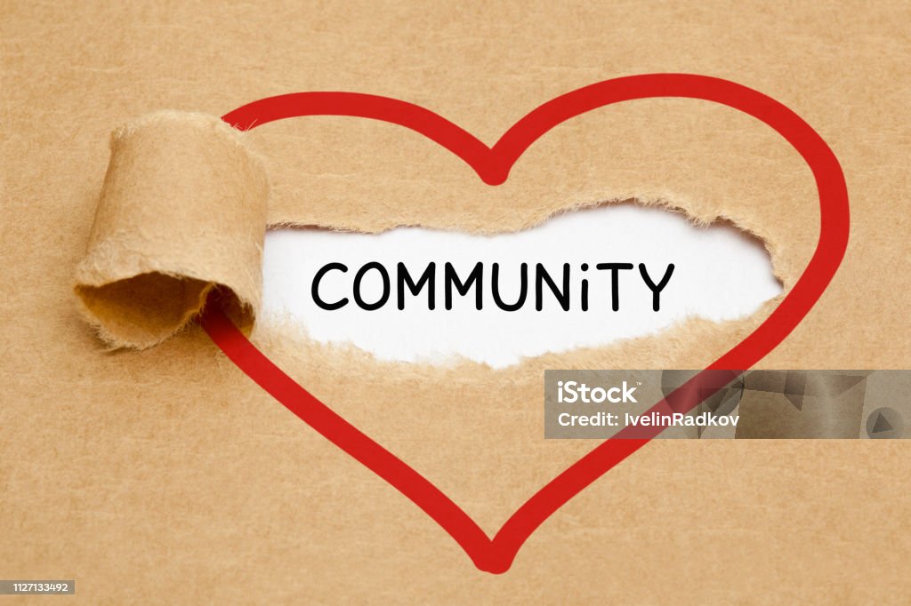 Community Ripped Heart Paper Concept Handwritten word Community appearing behind torn red heart on brown paper. Community Stock Photo